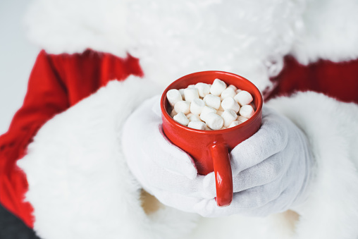 cropped shot of santa claus holding red cup with hot chocolate and marshmallows