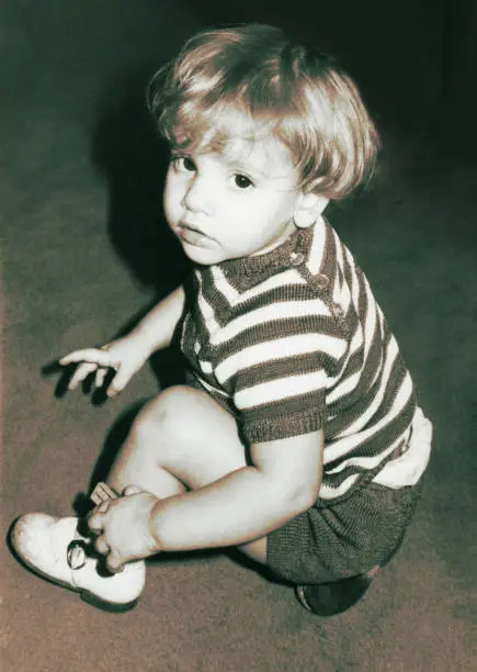 black and white toned image form the seventies of of a blond kid looking back at camera.