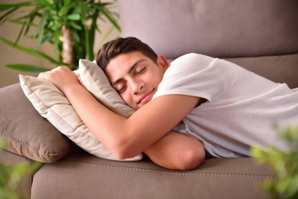 istock Man napping on a couch clinging to cushions at home 849846548