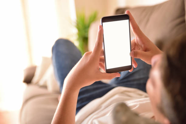 istock Young man watching multimedia content on a smartphone lying on a sofa 849846812