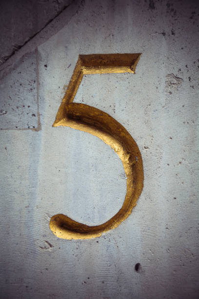 istock Carved golden number five on weathered white wall 849847316