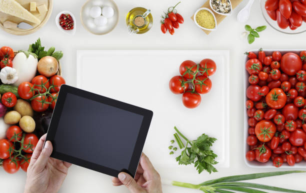 istock hands with digital tablet above on white cutting board with vegetables and tomatoes food ingredients on kitchen white worktop, copy space, top view 849870382