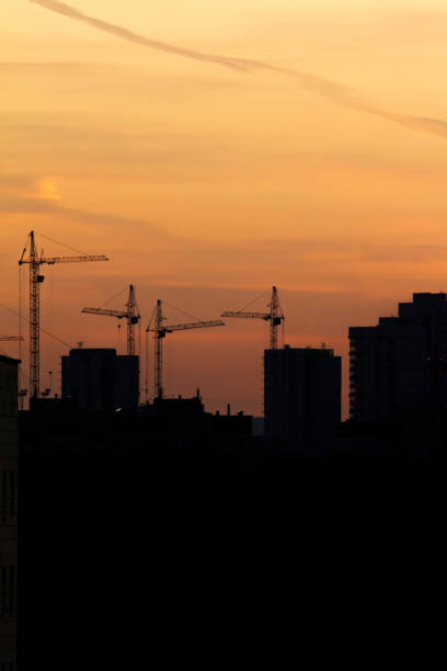 istock Construction cranes near residential apartments - view on sunrise, vertical 849874214