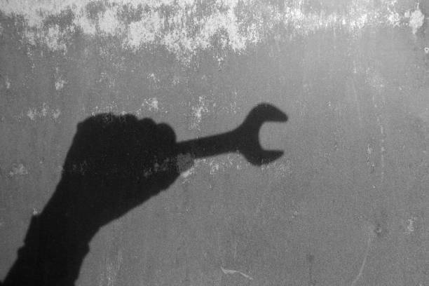 Repairing work spanner wrench tool in human hand - shadow the wall