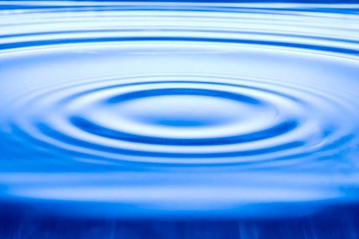 Water drop on water surface, Blue wave background.