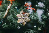 Gingerbread snowflake hanging on decorated Christmas tree