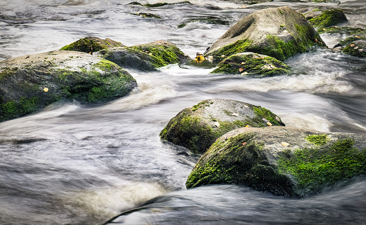 Waterfall in blurring with a flowing waters. Stones are around the waters