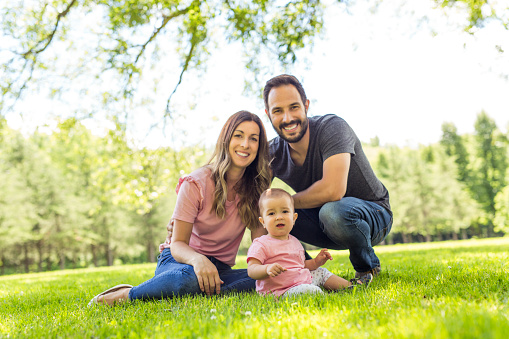 A Happy mother, father and daughter in the park. Beauty nature scene with family outdoor lifestyle