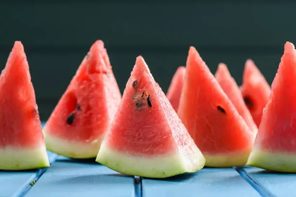 Helthy, refreshing summer snack. Fresh bright juicy watermelon slices with seeds on blue background closeup