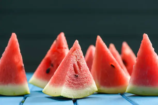 Bright organic watermelon cut into triangles on blue background with copyspace