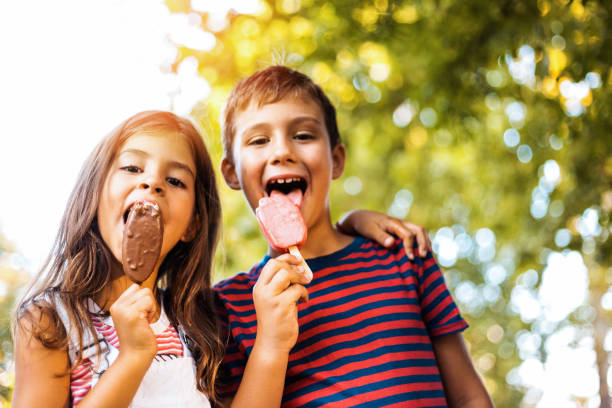 dwoje dzieci jedzących popsicle - lawn little girls small child zdjęcia i obrazy z banku zdjęć