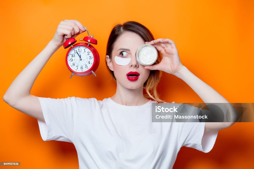 Woman using eye patch for her eyes and care lips on orange background Woman using eye patch for her eyes and care lips on orange background isolated. Portrait of natural  and true female as usually they are looks like Skin Stock Photo