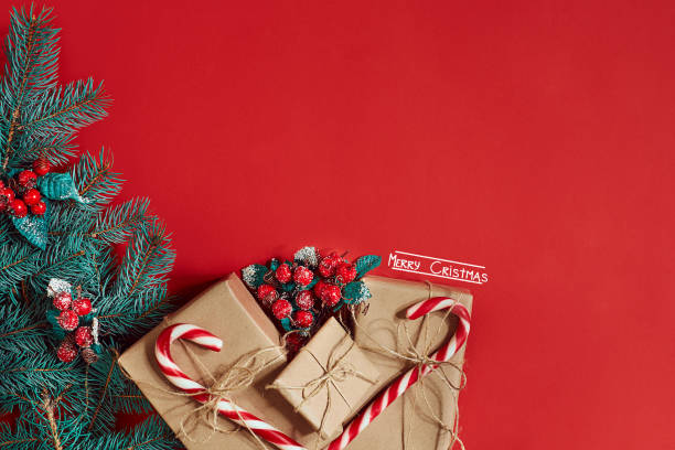 istock Christmas composition of pine cones, spruce branches and stack of gift boxes on red background 849934544