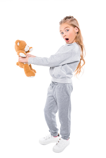 surprised little girl holding teddy bear and looking at camera isolated on white