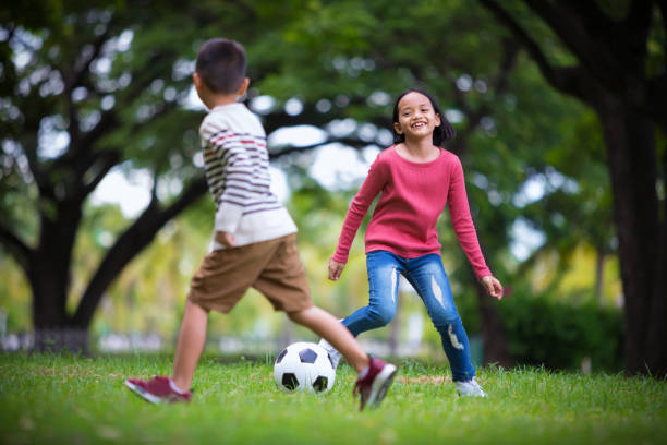 아시아 소년과 야외에서 축구 경기를 즐기는 여자 - 어린이 축구 뉴스 사진 이미지