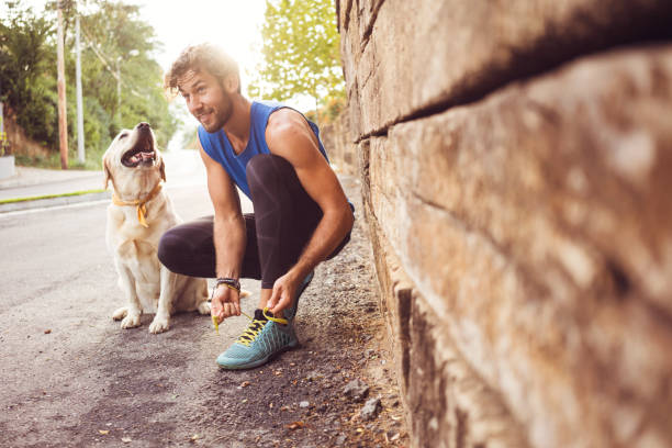 Jogging with my best friend Young man jogging with his dog jogging stock pictures, royalty-free photos & images