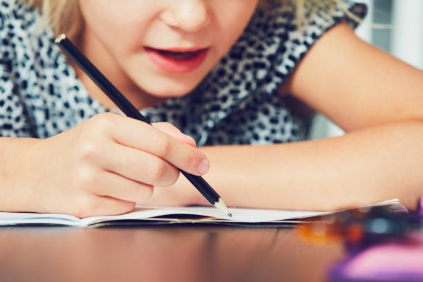 little girl doing homework - child thinking writing little girls imagens e fotografias de stock