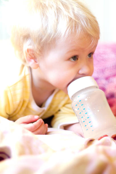 istock blonde child drinks infant formula from a bottle with a pacifier 850087428
