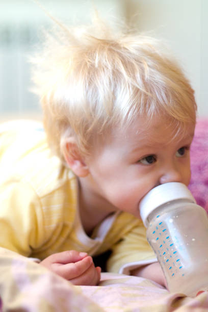 istock blonde child drinks infant formula from a bottle with a pacifier 850089344