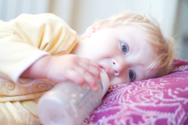 istock blonde child drinks infant formula from a bottle with a pacifier 850108832