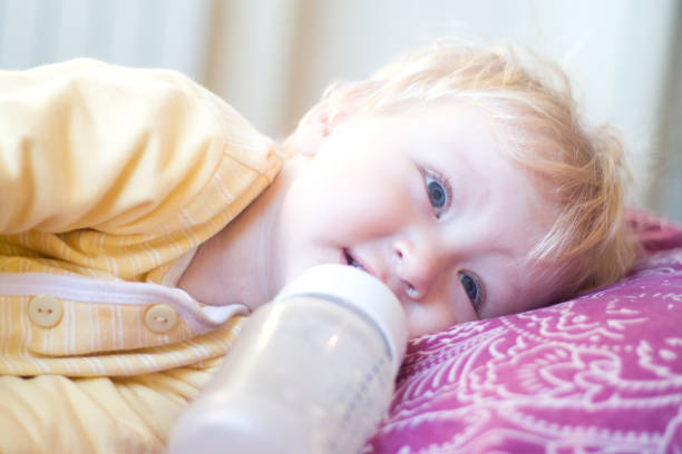 istock blonde child drinks infant formula from a bottle with a pacifier 850108900