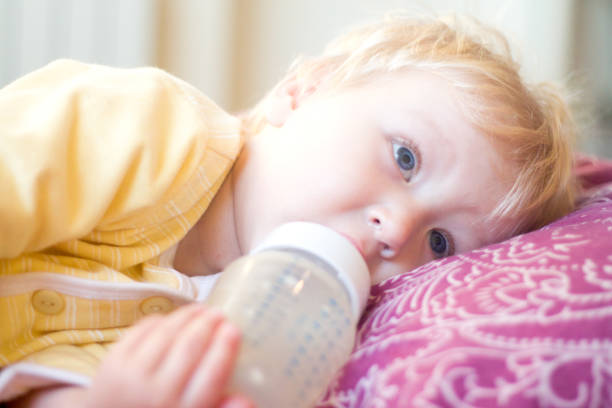 istock blonde child drinks infant formula from a bottle with a pacifier 850109804