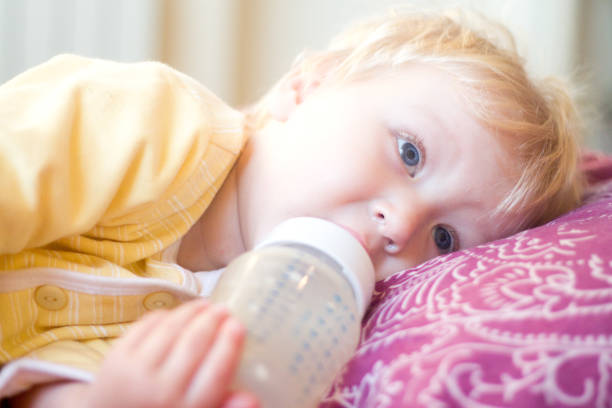 istock blonde child drinks infant formula from a bottle with a pacifier 850109876