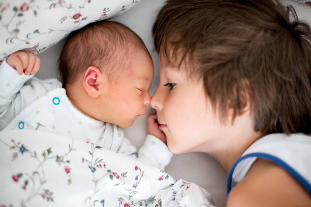 Beautiful boy, hugging with tenderness and care his newborn baby brother at home Beautiful boy, hugging with tenderness and care his newborn baby brother at home. Family love happiness concept brother stock pictures, royalty-free photos & images