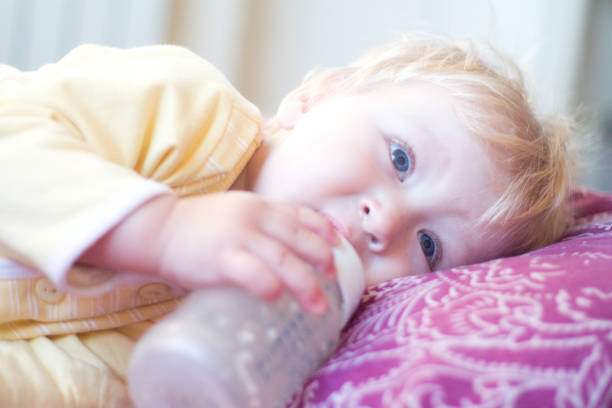 istock blonde child drinks infant formula from a bottle with a pacifier 850116802