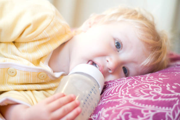 istock blonde child drinks infant formula from a bottle with a pacifier 850116874