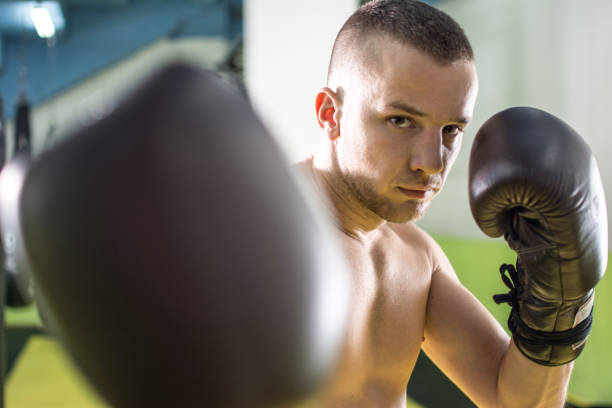 istock Shirtless handsome young man in gym giving punch towards camera. 850124564