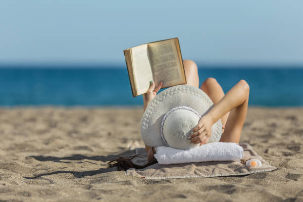 istock Woman on the beach reading a book 850124674