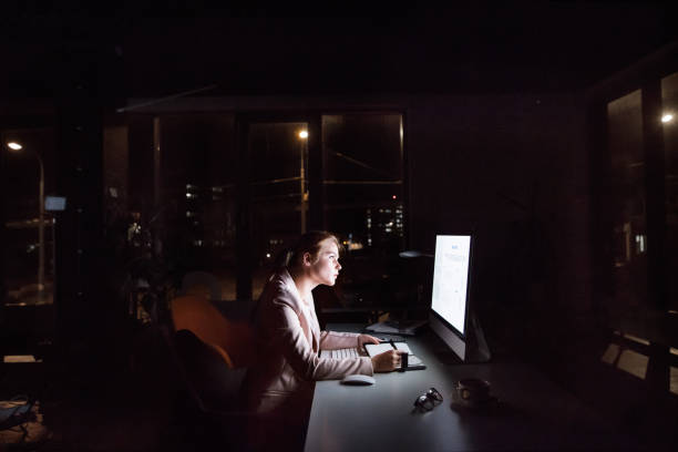 istock Businesswoman in front of computer screen in office at night. 850125464