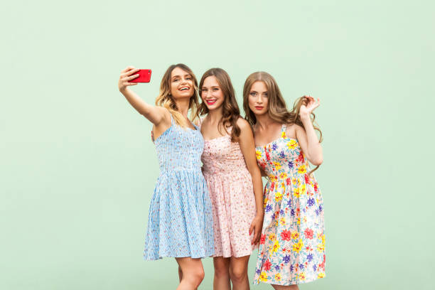 istock Three beautiful sisters in dress, macking selfie on green background, 850137312