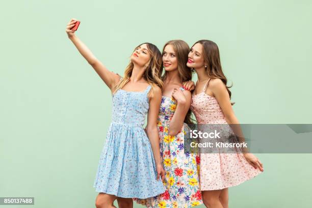 Hipsters Three Friends In Casual Dress Macking Selfie On Green Background And Have Fun Stock Photo - Download Image Now