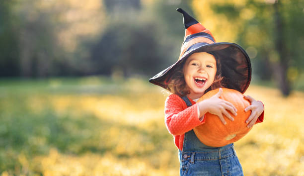 istock child girl with pumpkin outdoors in halloween 850142514