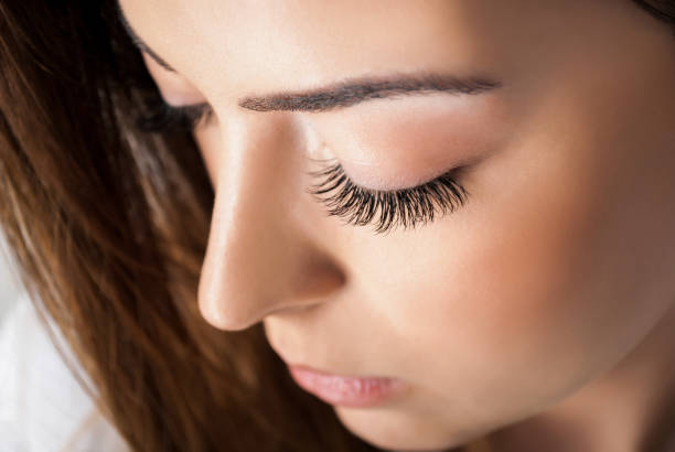 Beauty girl with extended silk eyelashes and eyes closed in a beauty studio, close up stock photo