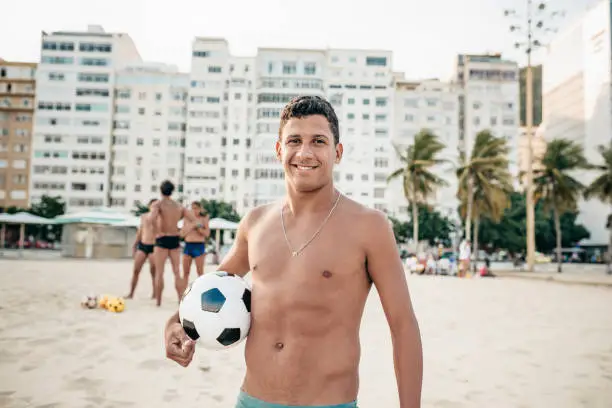 smiling brazilian man holding soccerball at copacabana beach in Rio de Janeiro