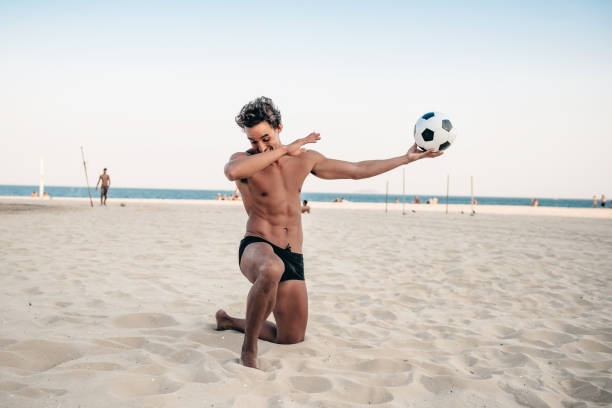 brasileño guapo sonriente posando con el balón de fútbol en la playa - beach football fotografías e imágenes de stock