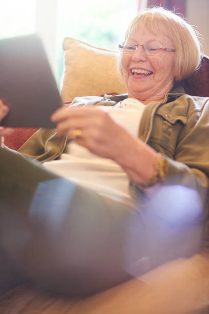 istock senior woman laughing as she uses digital tablet 850200548