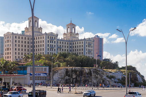 Views along the Malecon at Havana. A famous hotel on the background. Incidental people on the background.