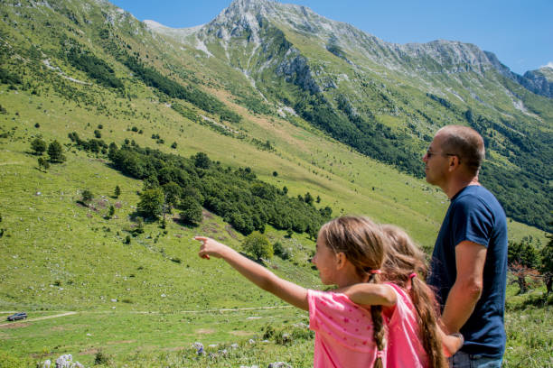 istock Single Father With Two Daughters Enjoying The View From The Mountain Meadow - Rear View 850273670