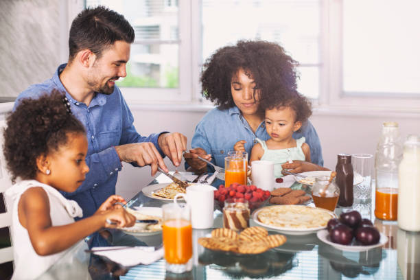 foto di una giovane famiglia felice che sta facendo colazione - women juice drinking breakfast foto e immagini stock