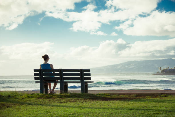 Girl enjoying beautiful scenery Girl sitting on park bench watching the sunset. sitting on bench stock pictures, royalty-free photos & images