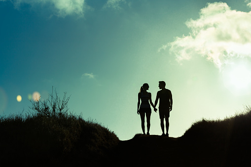 Young couple holding hands walking together on a country road.