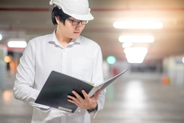 istock Young Asian Engineer or Architect holding files while wearing personal protective equipment safety helmet at construction site 850403082