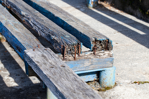 close-up photograph of a broken bench. Rusty nails connecting boards