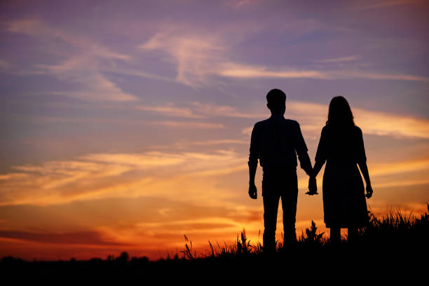 istock young couple is holding hands on a background sunset silhouette 850429358