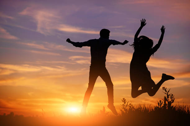 istock A young man with his girlfriend jump on background sunset silhouette 850429364