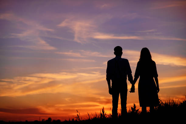 istock young couple is holding hands on a background sunset silhouette 850429382